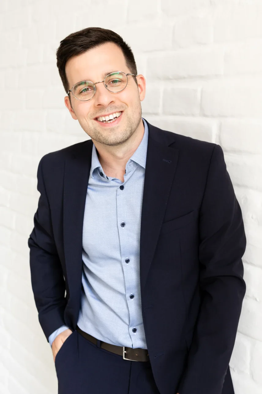 Portrait of Stefan Eipeltauer, founder and CEO of ARkid, in a navy jacket against a white brick wall.